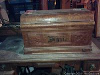 Front view of wooden cabinet cover with White branding and detailed carved trim showing scratches.