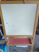 Whiteboard side of wooden easel showing red tray