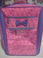 Front view showing polka-dot pattern, bow, zip pockets, brand label