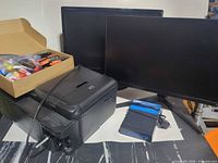 Lot overview showing two monitors, Canon printer, Linksys router, ink cartridges in box