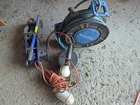 Group view of hose reel, extension cord, work light and scissor jack on floor
