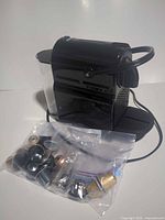 Actual black Vertuo Pop+ machine with attached water tank and bag of capsules