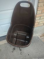 Front view of brown plastic garden cart showing interior seat and footrests