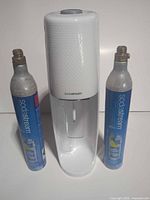 Front view of SodaStream machine flanked by two CO₂ cylinders