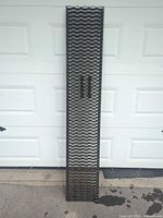 Full view of steel expanded-metal loading ramp leaning against garage door