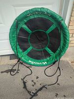 Full view of VivaActive green and black 40-inch saucer swing leaning against wall