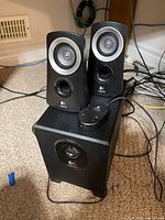 Front view showing two satellite speakers on top of subwoofer with control pod
