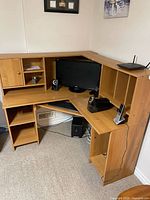 Full view of light wood L-shaped corner computer desk with hutch, slide-out keyboard tray and shelves