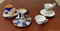 Overall view of four miniature cups with three saucers on tabletop