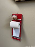 Front view of wall-mounted wooden memo roll holder showing cat ornament and paper roll