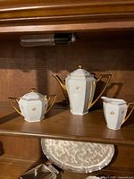 Teapot, sugar bowl and creamer on shelf showing design and condition