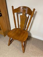 Full view of wooden spindle-back chair showing seat, backrest, legs and carved details