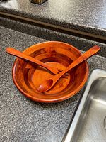 wooden bowl with spoon and fork resting inside on countertop