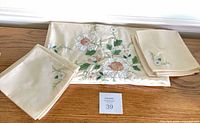 Tablecloth folded with two napkins showing embroidery
