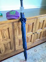 Umbrella folded standing next to cap on cabinet