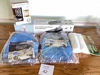 Lot overview showing all packaged items: two microfiber mitts, floor scrub brush with squeegee, mop covers pack, wax warmer box