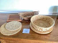 Group shot showing all items: two wicker baskets, bamboo tray beneath round basket, wood trivet, two woven coasters