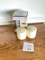 Boxed ScentSationals warmer beside two ivory pillar candles on table