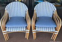 Front view showing two of the rattan chairs stacked, wicker pattern and cushions visible