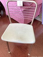 Single chair front view showing brass tone frame, cream vinyl seat