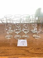 Eight clear stemmed goblets on wooden surface