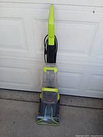 Full view of BISSELL upright carpet cleaner standing against garage door