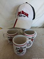 Hat positioned above three Jim Beam mugs