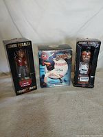 Three boxed bobbleheads standing side by side