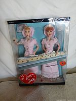 Front view of boxed set showing both dolls and conveyor belt accessory
