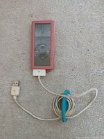 Front view of pink iPod Nano in silicone case with attached 30-pin USB cable and blue organizer