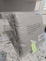 Comforter sealed in clear plastic bag, gray color, folded compactly