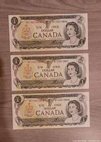 Front view of all three consecutive 1973 $1 notes showing serial numbers and Queen Elizabeth II portrait