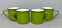 Four matching green enamel mugs front view