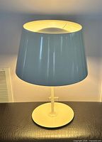 Frontal lit view of Ikea Kulla lamp showing white shade, stem and base