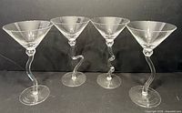 Front view of four identical crystal martini glasses with twisted stems