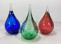 front view of three coloured teardrop paperweights