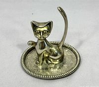 Front view of brass cat ring holder on engraved tray