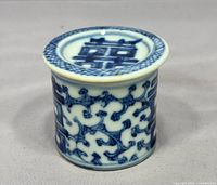 Front view of cylindrical blue & white porcelain lidded jar showing double happiness symbol and vine pattern