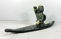 Side view of entire soapstone sculpture showing hunter in kayak with harpoon and seal