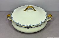 Top view of covered bowl showing handles, lid finial and border design