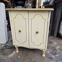 front angled view of cream bedside table showing gold trim and two doors