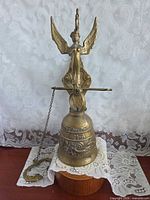 Full view of brass monastery bell with finial, chain and bracket
