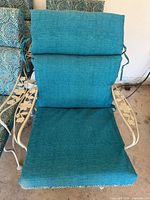 Front view of one chair showing solid teal side of cushion and floral arm detail