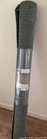 Rolled rug standing upright in packaging