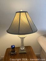 Lamp displayed with shade and lit bulb on side table