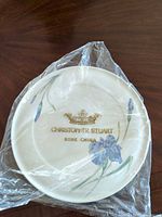 Front view of Christopher Stuart Iris bone china plate in plastic wrap