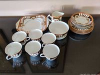 Entire tea set laid out: cups, saucers, tray, bowl, creamer