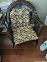 Full view of wicker rattan armchair with floral cushions