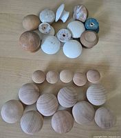 Top view of all 26 wooden knobs in two groups highlighting finishes and drilled holes