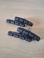 Four black rubber brake pads laid flat showing contact surface